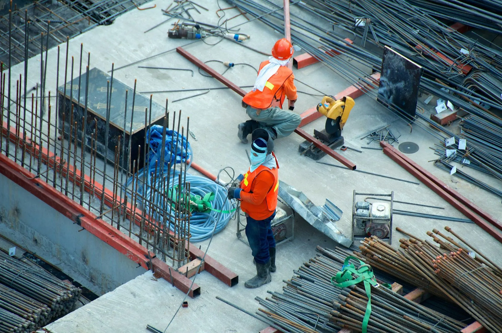 Construction crew in hi-vis vests tying steel rebar across a concrete slab foundation