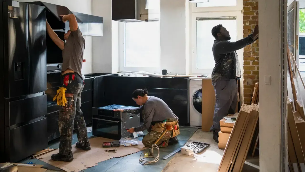 Carpenters installing dark wood cabinets during a kitchen remodel