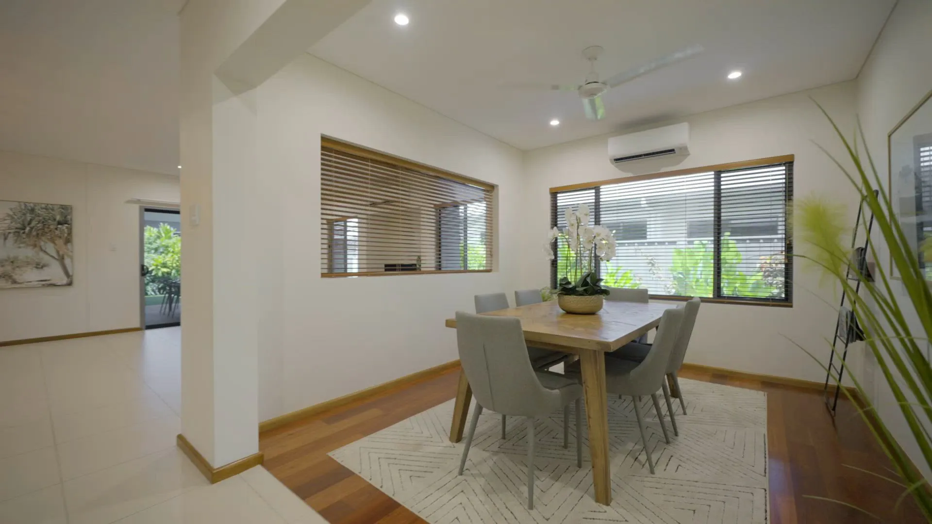 Open-plan dining area with hardwood floors and tall windows in a renovated home