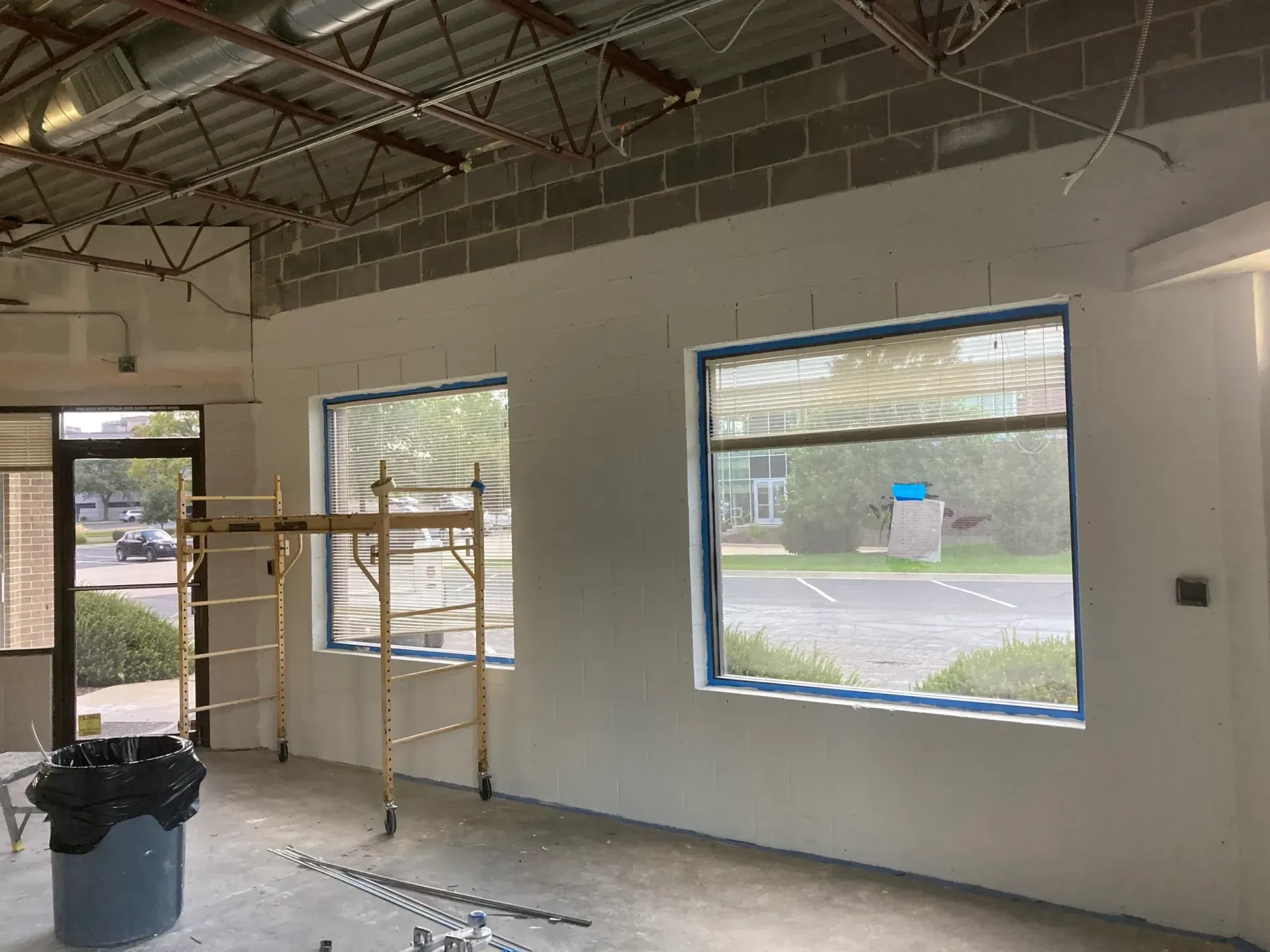Commercial interior build-out with new drywall, tall windows and scaffolding
