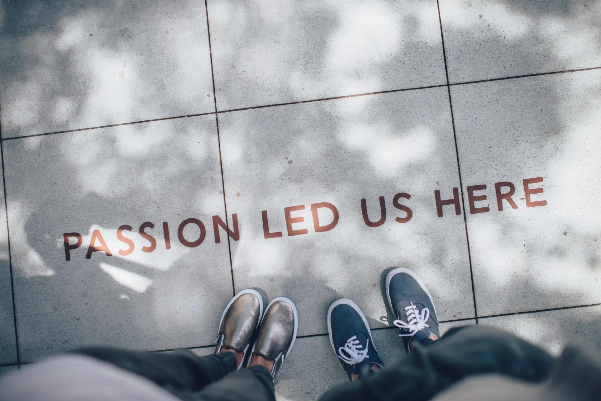 “Passion led us here” painted on pavement between two people standing on it