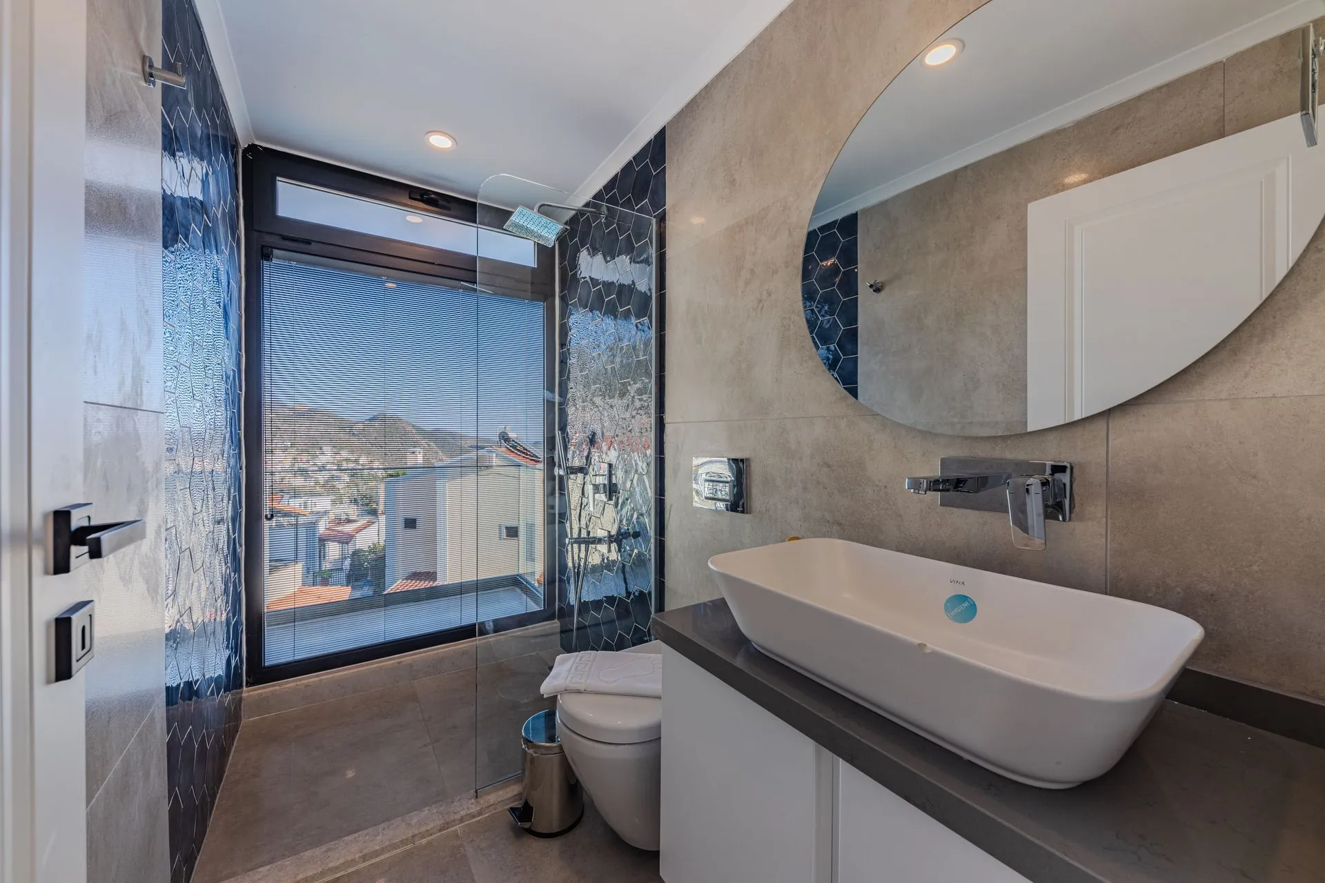 Modern bathroom remodel with a vessel sink, round mirror and glass walk-in shower