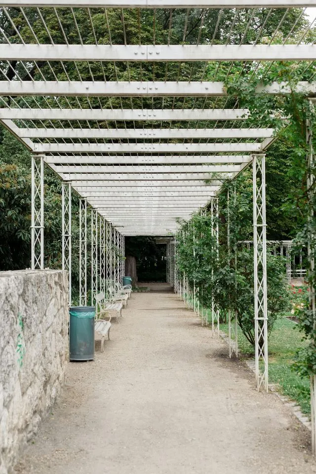 White metal pergola walkway running over a gravel garden path
