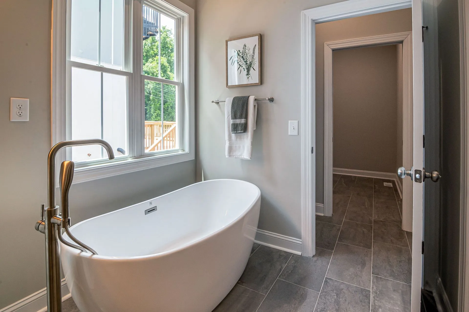 Freestanding soaking tub with a floor-mounted filler in a tiled bathroom