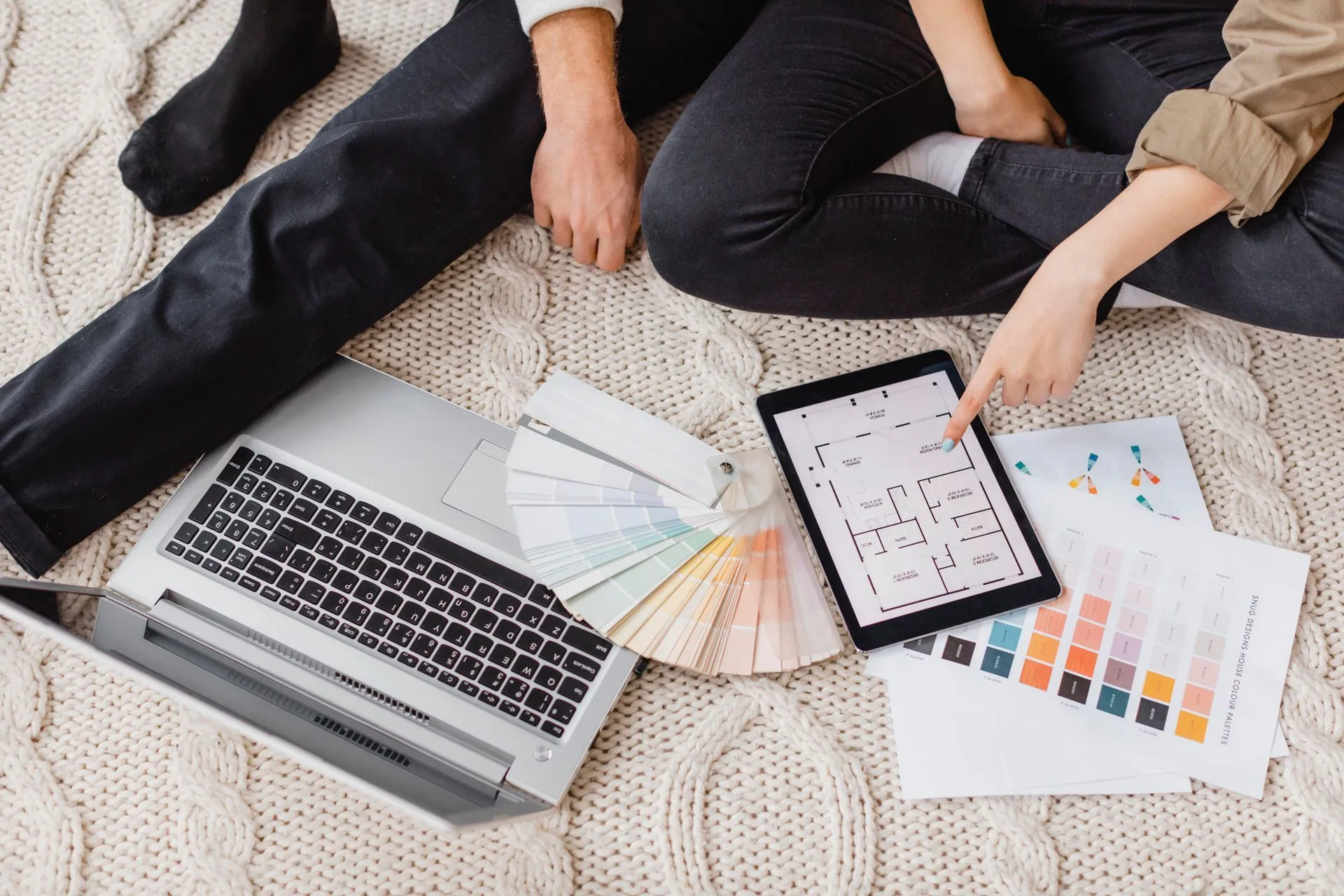 Couple planning a home renovation with paint swatches, a laptop and a floor plan