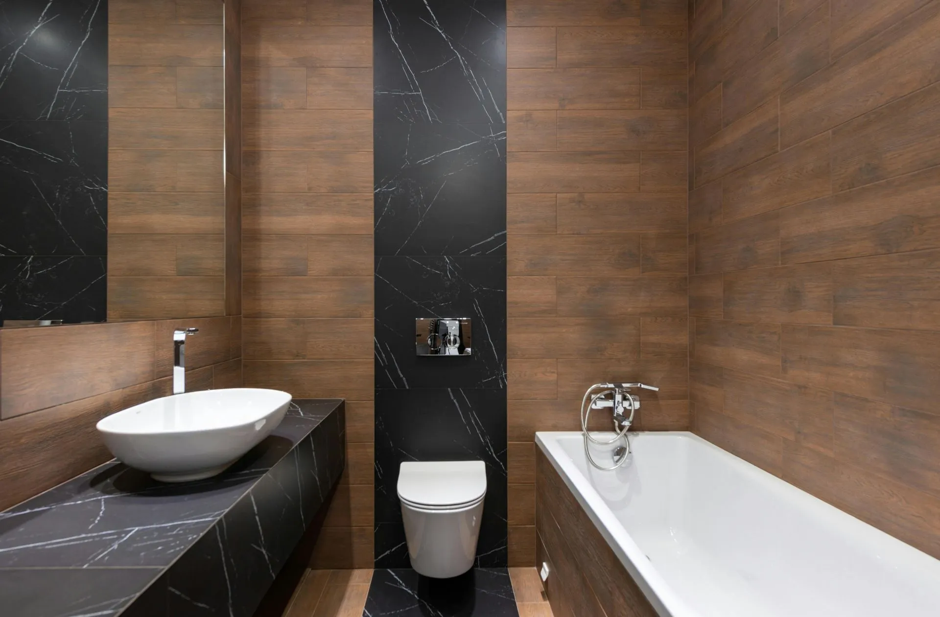 Bathroom with black marble walls, a wood-look accent wall, vessel sink and soaking tub
