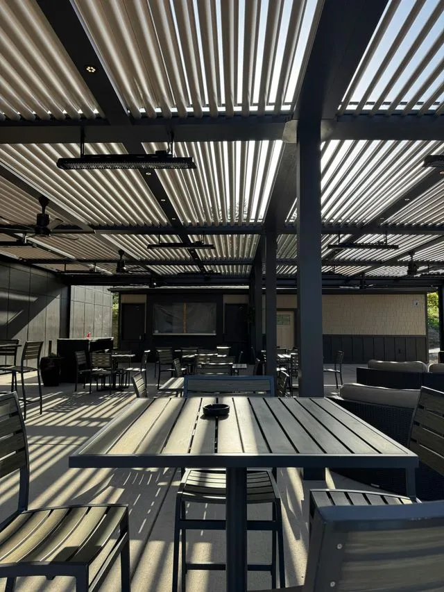 Louvered aluminum pergola shading a patio with dining tables and lounge seating