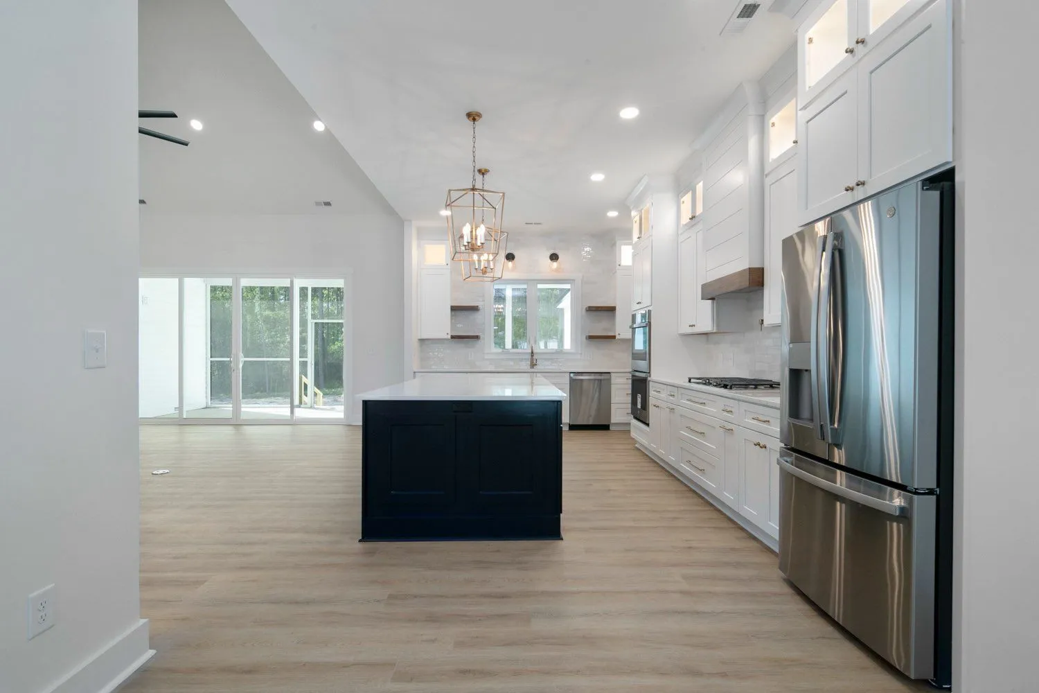 White kitchen remodel with a navy island, open shelving and stainless appliances