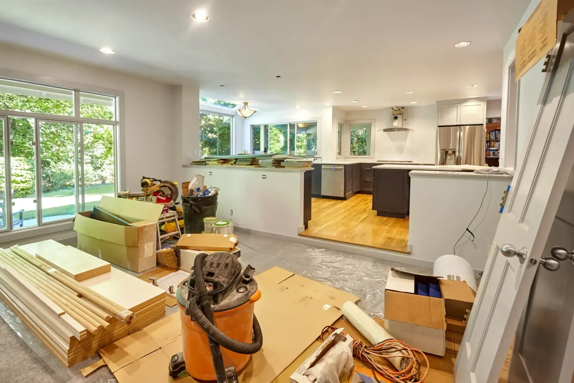Kitchen and living area mid-remodel with lumber, tools and a shop vacuum