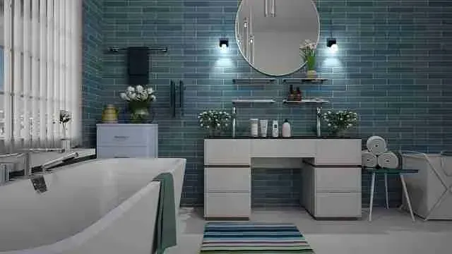 Bathroom remodel with teal subway tile, a round mirror and a freestanding tub