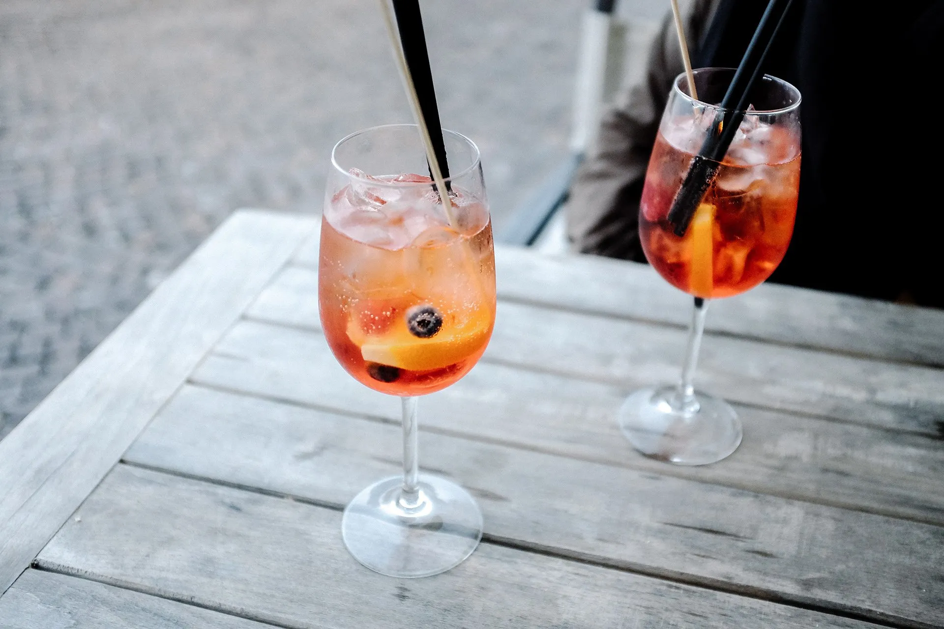 Two spritz cocktails on a wooden patio table on a sunny afternoon